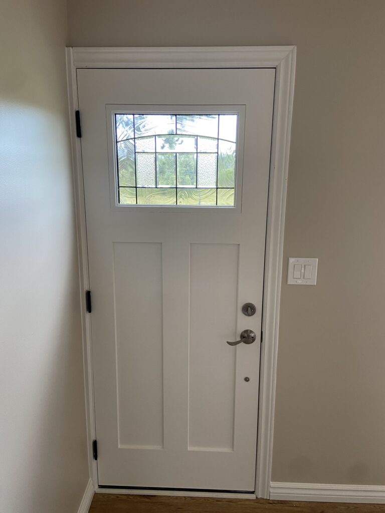 After renovation — bright modern-farmhouse room with warm greige walls, white trim and plank ceiling.