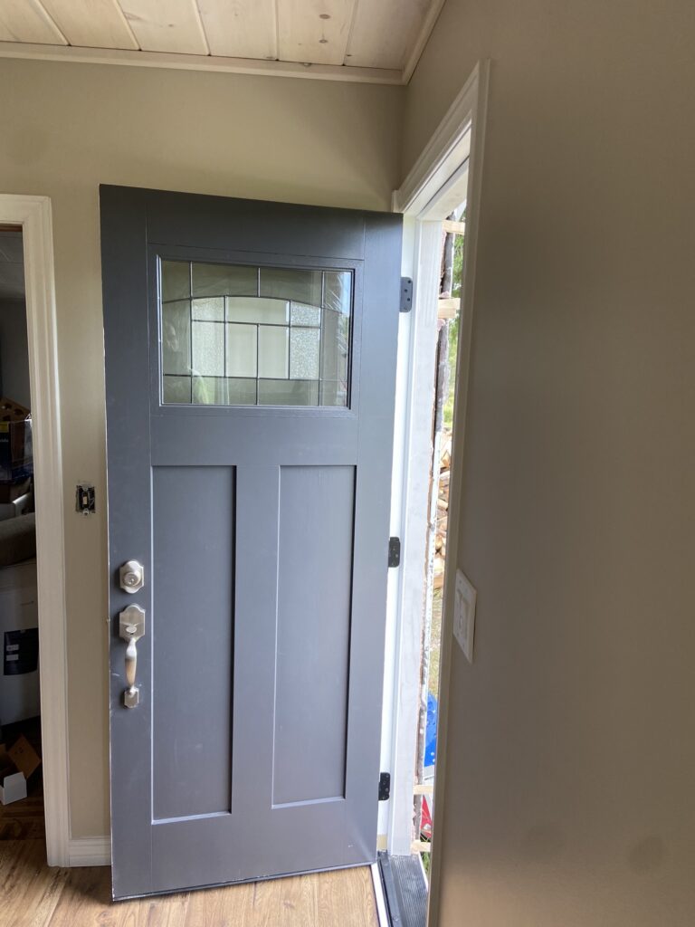 Finished modern-farmhouse room with craftsman grey entry door, whitewashed plank ceiling and wood-look floors in Mattawa, Ontario.