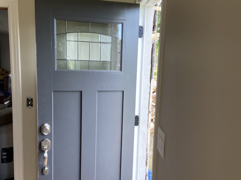 Finished modern-farmhouse room with craftsman grey entry door, whitewashed plank ceiling and wood-look floors in Mattawa, Ontario.