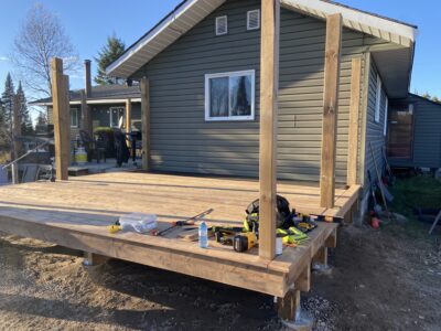 Pressure-treated deck boards partly installed across the joists with posts in place at golden hour