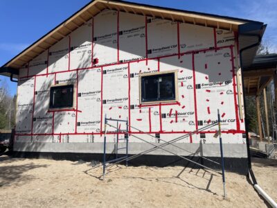 Gable end of a home sheathed in continuous rigid foam insulation with two new black windows