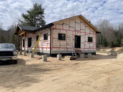 New home wrapped in rigid foam insulation with a covered porch and finished metal roof