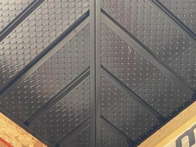 Close-up of black vented metal soffit panels meeting at an eave corner