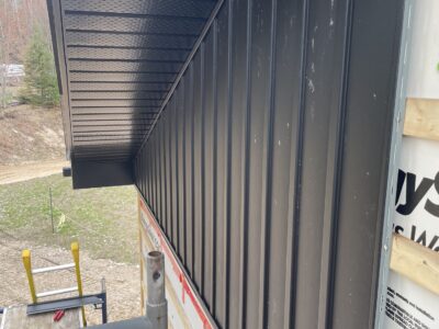 Black board-and-batten steel siding installed beneath a black metal soffit