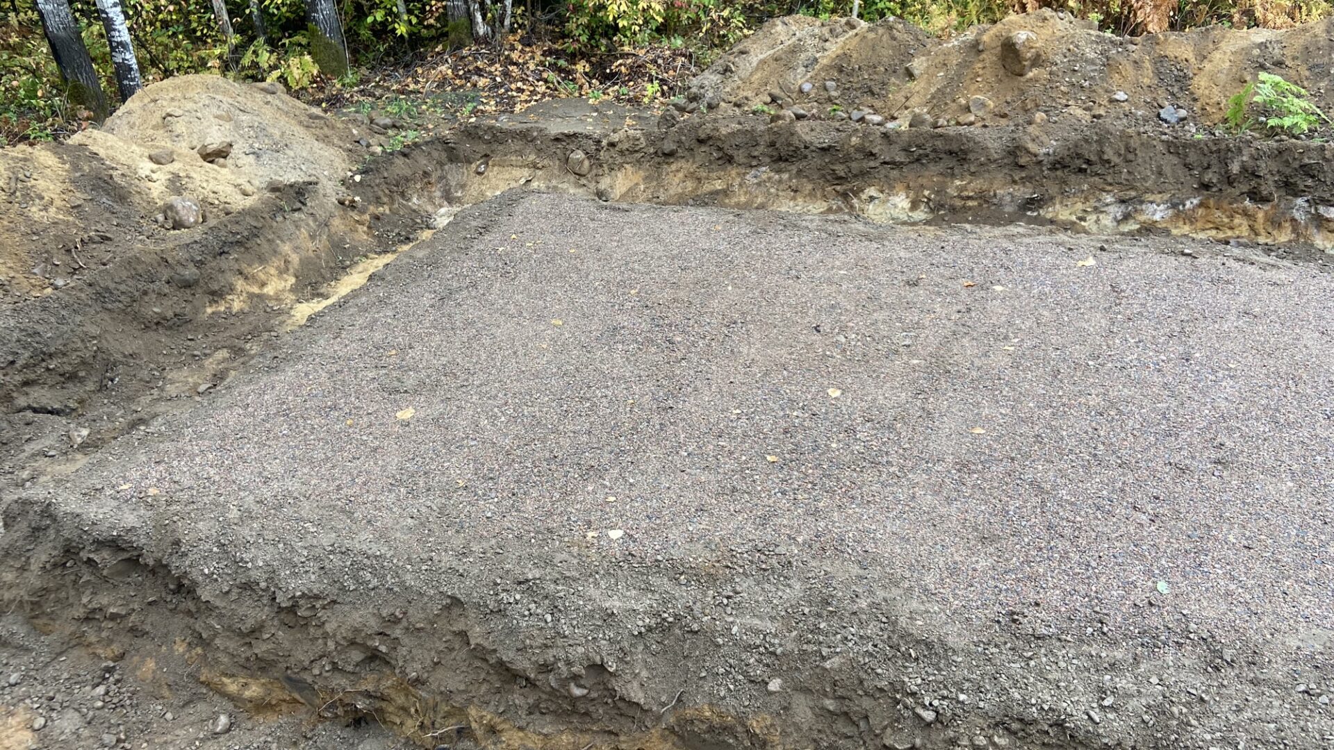 Excavated building pad with a compacted gravel base ready for foundation work