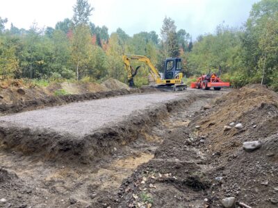 An excavator and compact tractor grading the cleared garage site