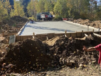Freshly poured concrete garage slab curing within the forms