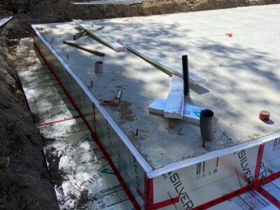 Cured slab edge wrapped in rigid foam board with plumbing rough-ins