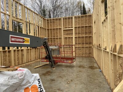 Interior of the framed garage with OSB-sheathed walls and a boom lift
