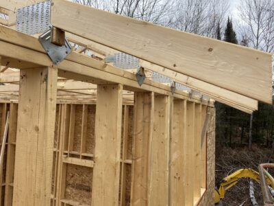 Close-up of roof framing with galvanized connector plates at the top plate