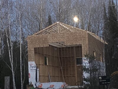 Framed two-storey garage at dusk, sheathed with house wrap started