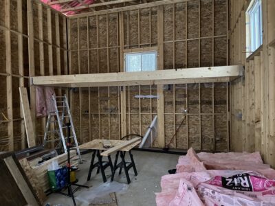 Garage interior with a loft floor beam, window, and batt insulation staged