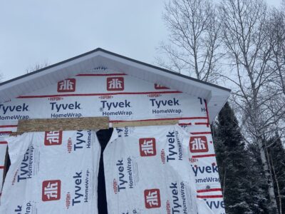 Front gable wrapped in house wrap with finished trim and snow on the ground