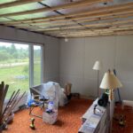 Room with fresh drywall on the walls and wood strapping over foil insulation on the ceiling