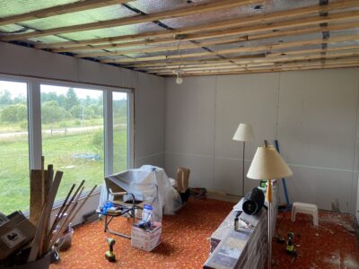 Room with fresh drywall on the walls and wood strapping over foil insulation on the ceiling