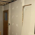 Newly hung drywall taped and mudded around an interior doorway
