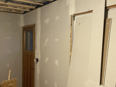 Newly hung drywall taped and mudded around an interior doorway
