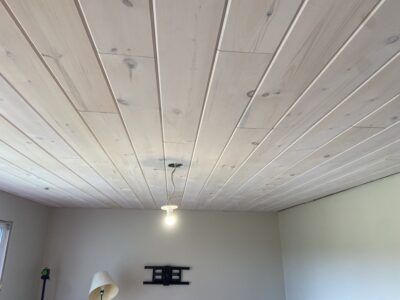 Finished whitewashed plank ceiling with a pendant light and a wall-mounted TV bracket