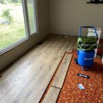 Wood-look laminate plank flooring being installed over the old flooring