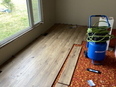 Wood-look laminate plank flooring being installed over the old flooring