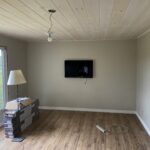 Finished living room with a plank ceiling, crown molding, mounted TV, and new wood-look floor