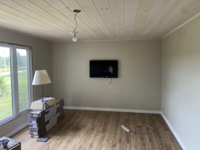 Finished living room with a plank ceiling, crown molding, mounted TV, and new wood-look floor