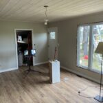 Finished open living space with a plank ceiling, new flooring, and a craftsman entry door