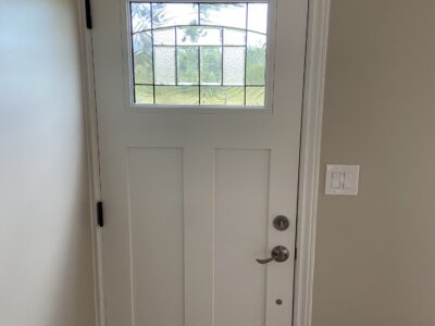 Interior view of a new white craftsman entry door with decorative leaded glass